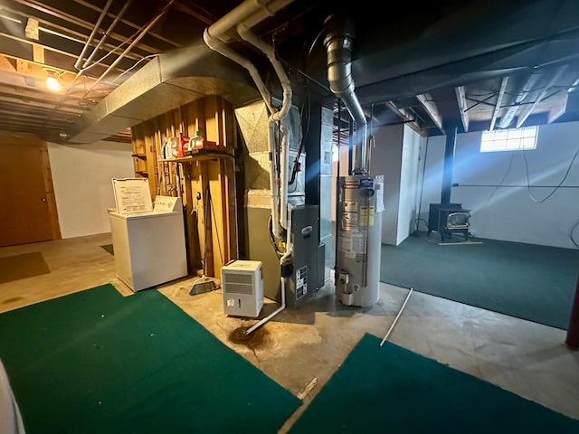 basement with heating unit, washer and clothes dryer, gas water heater, and a wood stove