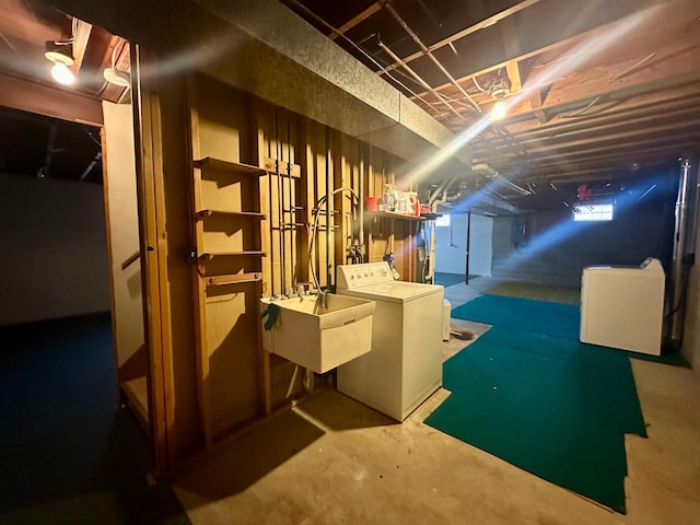 basement featuring sink, washer and clothes dryer, and refrigerator