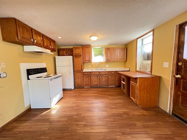 kitchen featuring hardwood / wood-style flooring, sink, a textured ceiling, and white appliances