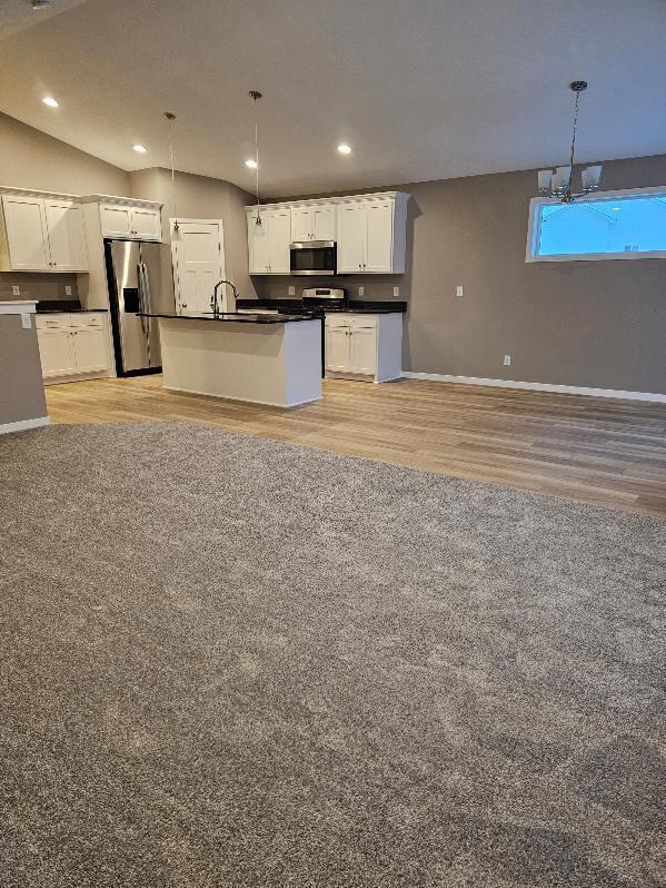 kitchen featuring hanging light fixtures, white cabinetry, appliances with stainless steel finishes, and light wood-type flooring