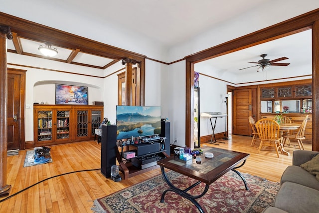 living room featuring wood-type flooring, crown molding, and a ceiling fan