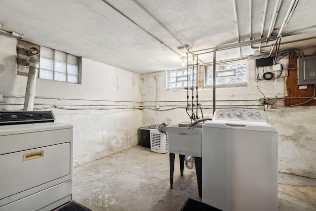 below grade area featuring electric panel, a sink, and washing machine and clothes dryer