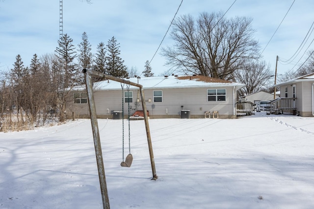 snow covered rear of property featuring central AC unit