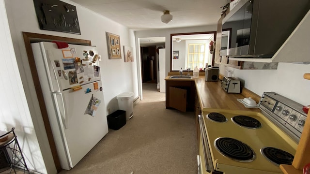 kitchen with white refrigerator, range, sink, and light carpet