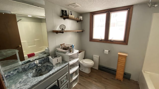 full bathroom with shower / bathing tub combination, wood-type flooring, baseboard heating, toilet, and a textured ceiling