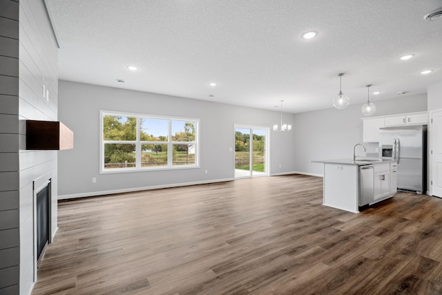 unfurnished living room with dark hardwood / wood-style flooring, sink, a fireplace, and a textured ceiling