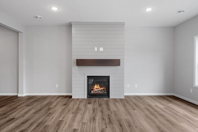 unfurnished living room featuring a fireplace and light hardwood / wood-style flooring