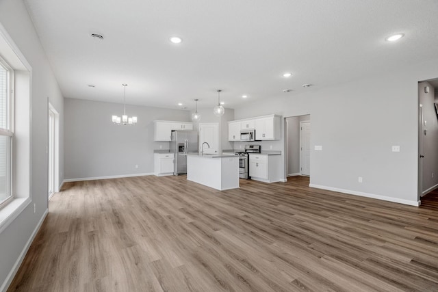 unfurnished living room with light wood-type flooring, sink, and a chandelier