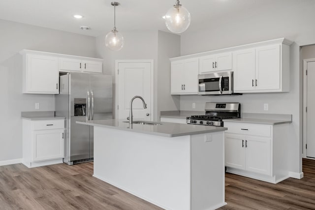 kitchen with sink, hanging light fixtures, stainless steel appliances, white cabinets, and a center island with sink