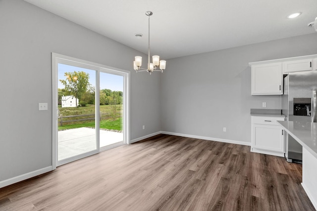 interior space featuring stainless steel refrigerator with ice dispenser, white cabinetry, hardwood / wood-style floors, and hanging light fixtures