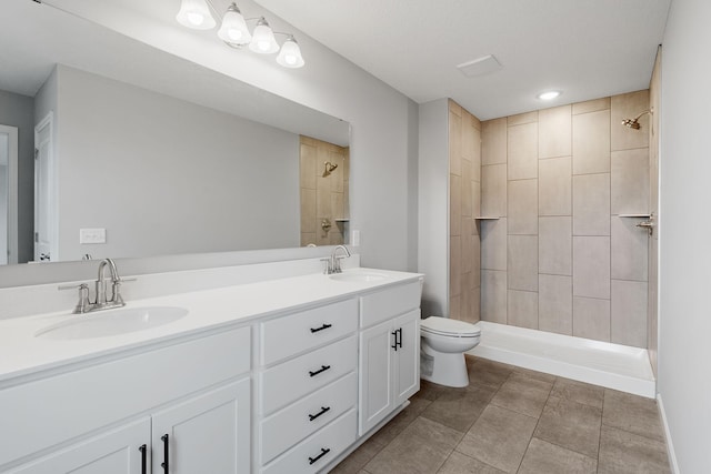 bathroom with vanity, tile patterned floors, toilet, and tiled shower