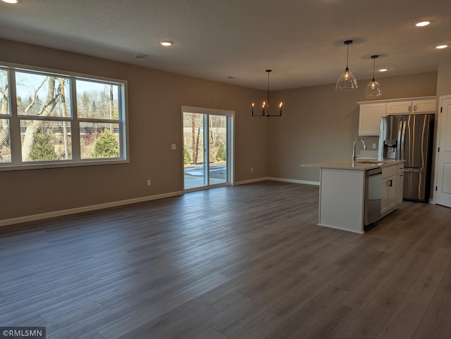 kitchen with an inviting chandelier, dark wood-style flooring, appliances with stainless steel finishes, white cabinetry, and open floor plan