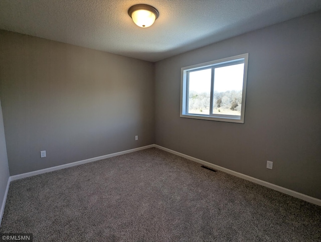 carpeted spare room with visible vents, baseboards, and a textured ceiling