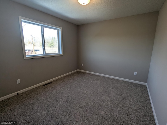 carpeted spare room with visible vents, baseboards, and a textured ceiling