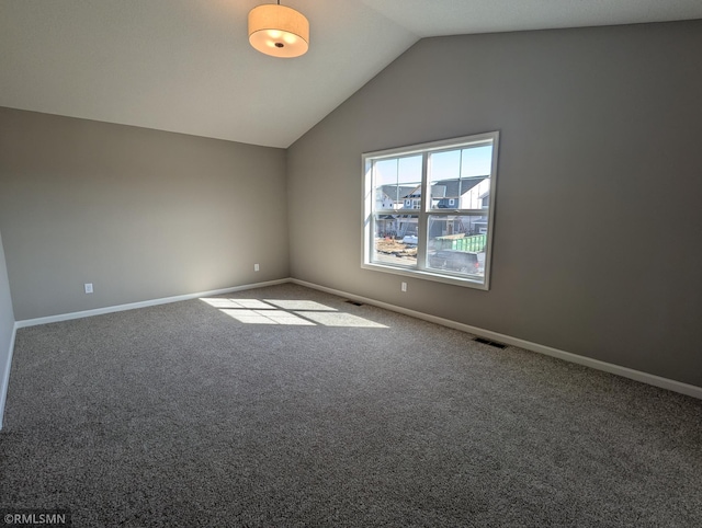 empty room featuring visible vents, baseboards, carpet, and vaulted ceiling