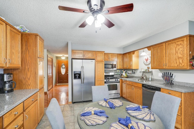 kitchen featuring sink, light tile patterned floors, stainless steel appliances, and a textured ceiling