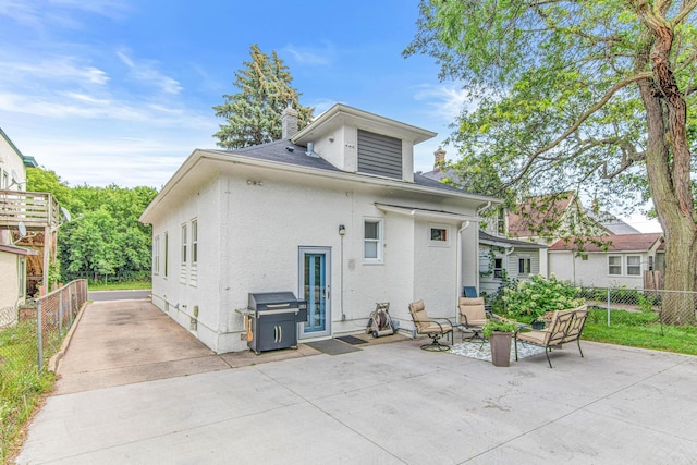 back of house featuring stucco siding, a patio, a chimney, and fence