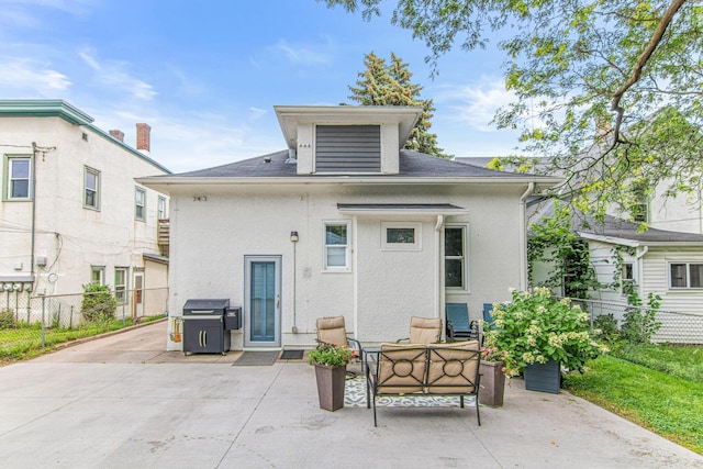 rear view of house featuring stucco siding, fence, and a patio