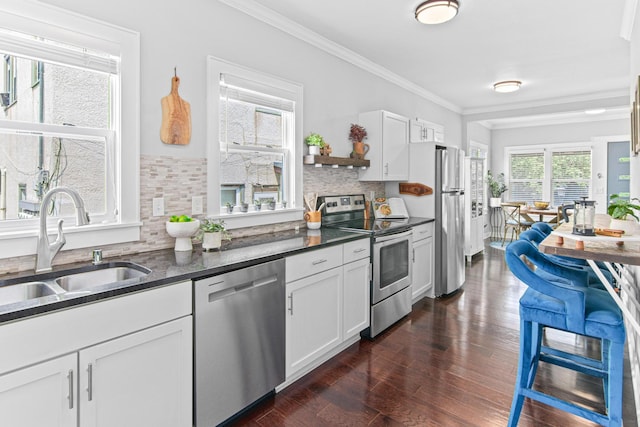 kitchen with appliances with stainless steel finishes, dark wood-style flooring, a sink, and crown molding