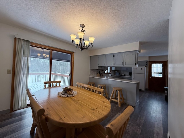 dining room featuring a textured ceiling, dark wood-type flooring, and a chandelier