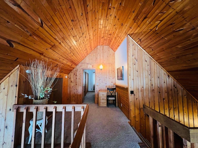 hall with vaulted ceiling, wooden ceiling, dark carpet, and wood walls