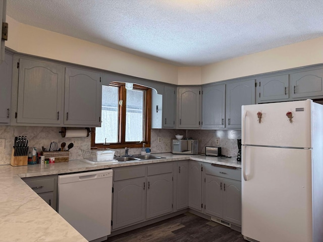 kitchen with gray cabinetry, sink, white appliances, and tasteful backsplash