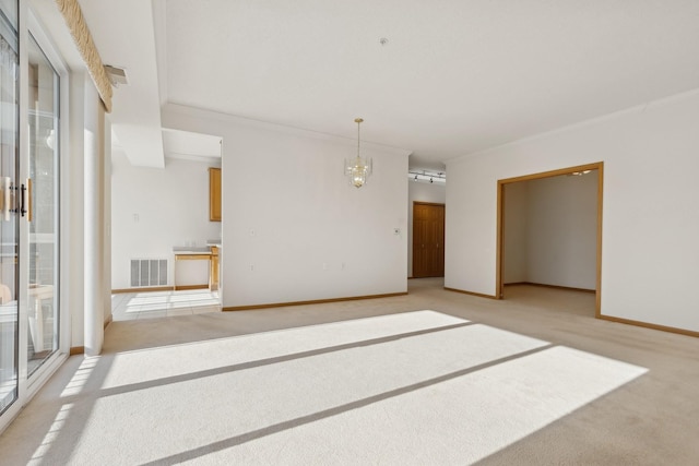 spare room with light carpet, an inviting chandelier, visible vents, and a wealth of natural light