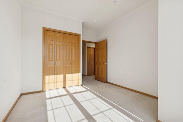 unfurnished bedroom with carpet, a closet, ornamental molding, and baseboards