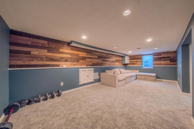 carpeted cinema room featuring wooden walls and a textured ceiling