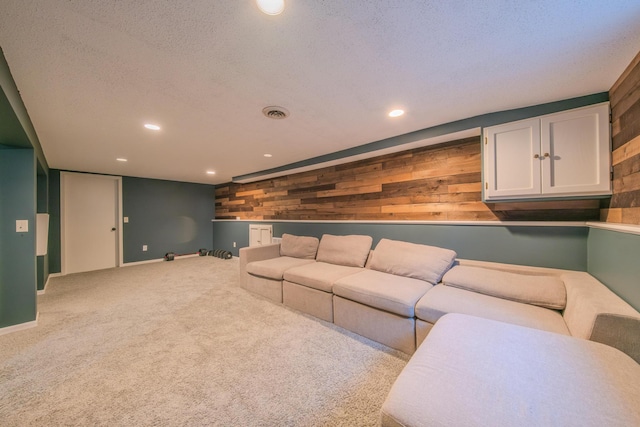 living room with light carpet, a textured ceiling, and wooden walls