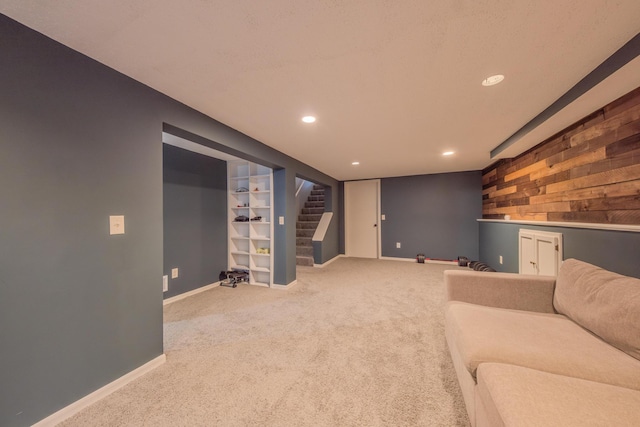 living room with built in shelves, wooden walls, and carpet