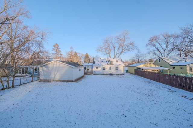 snow covered back of property featuring a storage unit