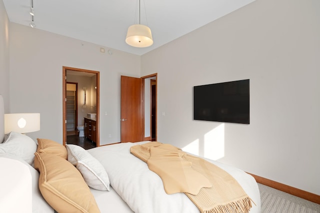 bedroom featuring rail lighting, carpet flooring, and ensuite bath