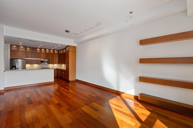 unfurnished living room featuring dark hardwood / wood-style flooring and rail lighting