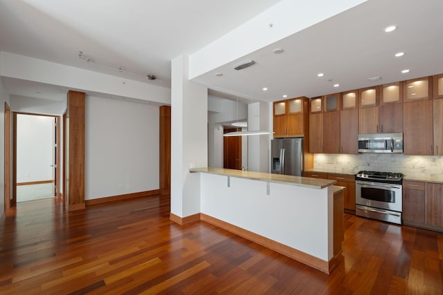 kitchen with a breakfast bar, dark hardwood / wood-style floors, kitchen peninsula, stainless steel appliances, and backsplash