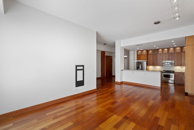 unfurnished living room with track lighting and dark hardwood / wood-style floors