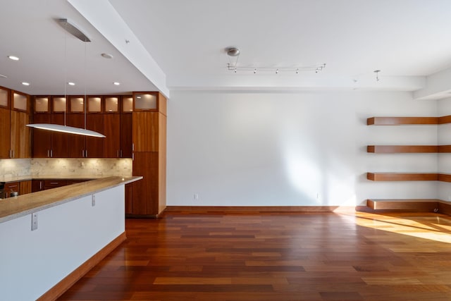 kitchen with pendant lighting, dark hardwood / wood-style floors, light stone countertops, and decorative backsplash