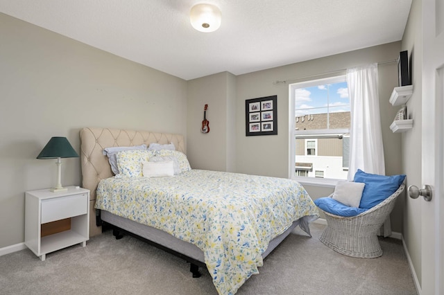 bedroom with light carpet, baseboards, and a textured ceiling