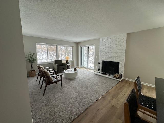 living room featuring a brick fireplace, hardwood / wood-style floors, and a textured ceiling