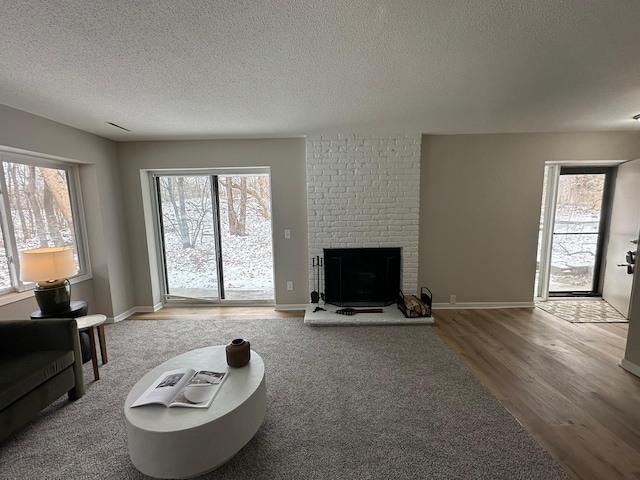 living room featuring wood-type flooring, plenty of natural light, a textured ceiling, and a fireplace