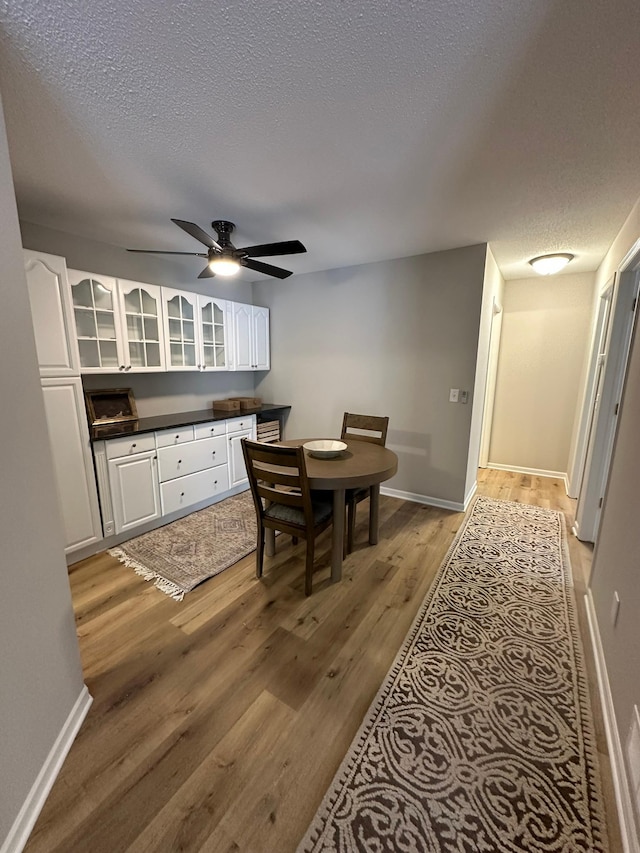 dining room featuring ceiling fan, a textured ceiling, and light hardwood / wood-style floors