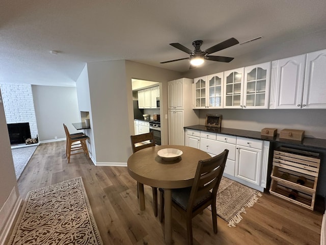 dining space with ceiling fan, hardwood / wood-style floors, and a fireplace