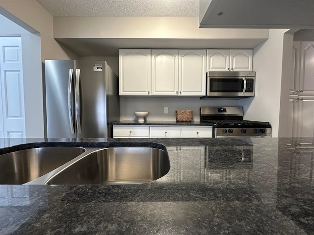 kitchen featuring sink, stainless steel appliances, dark stone counters, and white cabinets