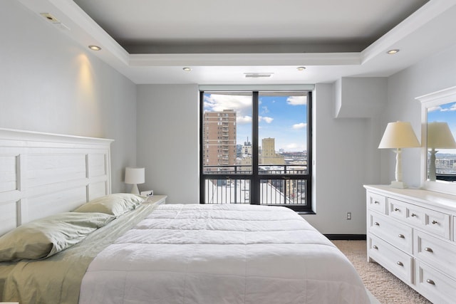 bedroom featuring multiple windows, light carpet, and a tray ceiling