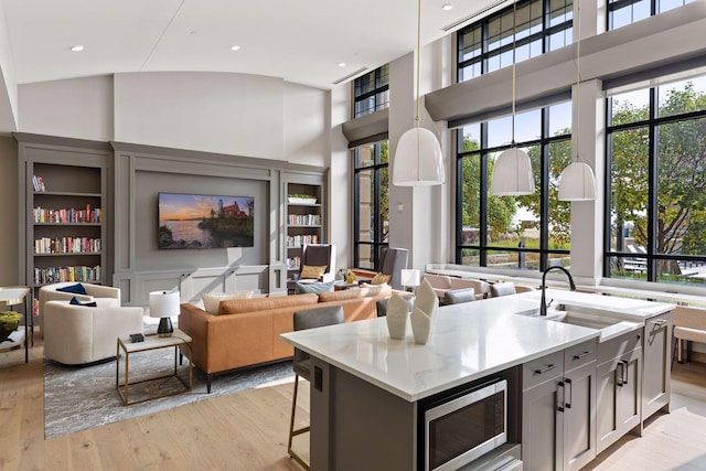 kitchen with sink, a breakfast bar area, a kitchen island with sink, decorative light fixtures, and light wood-type flooring