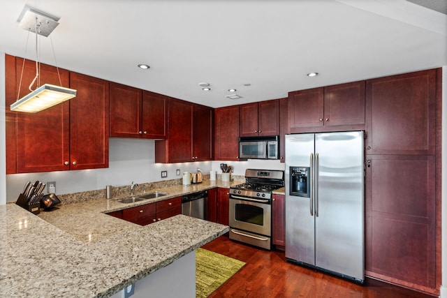 kitchen featuring pendant lighting, stainless steel appliances, kitchen peninsula, and sink