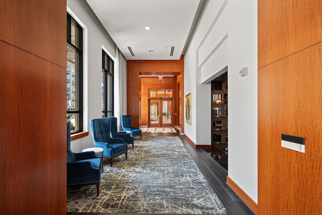 hallway featuring dark wood-type flooring and wood walls