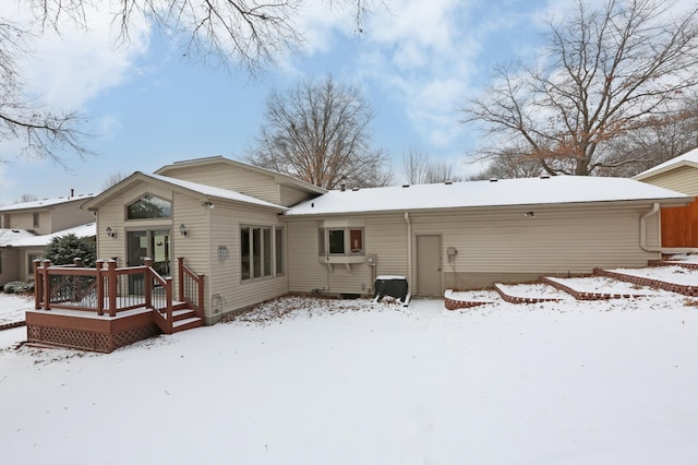 snow covered rear of property with a deck