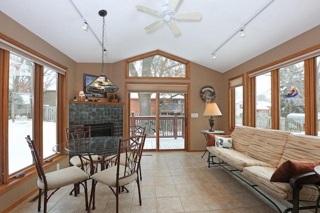 dining space featuring a fireplace, lofted ceiling, light tile patterned floors, ceiling fan, and track lighting