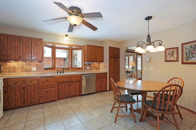 kitchen with light tile patterned flooring, sink, tasteful backsplash, decorative light fixtures, and dishwasher